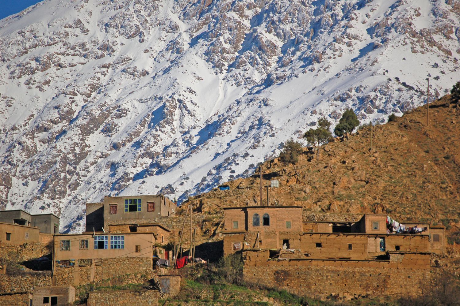 Berber village stone houses below snow-dusted peaks in the High Atlas